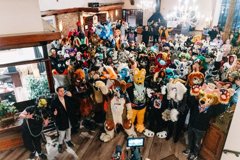 A big group of fursuiters gathered in a lodge lobby, seen from above