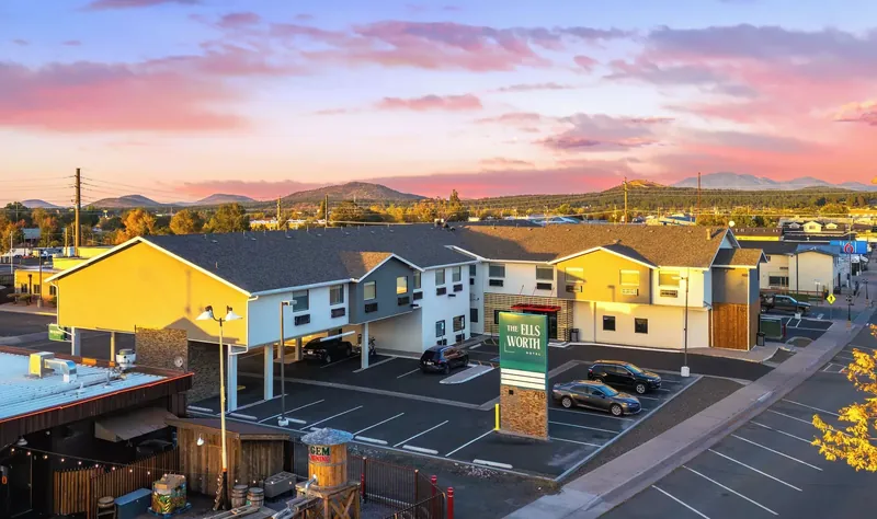 The Ellsworth Hotel from above at sunset, its green sign by the road and mountains on the horizon